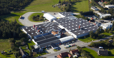 Aerial view of the company's headquarters, showcasing a large, modern facility surrounded by greenery.