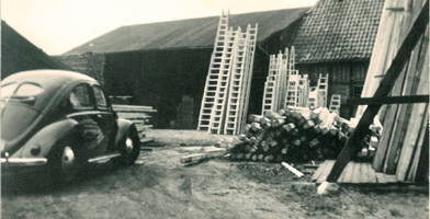 Historical photo of the DOLLE Group, featuring vintage vehicles and industrial structures.