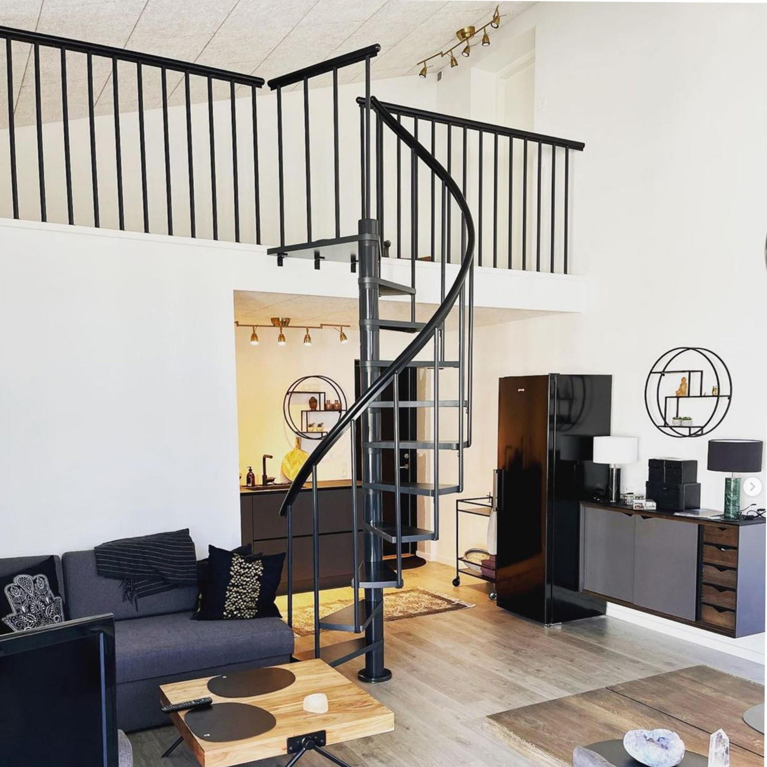 Black metal spiral staircase in a contemporary living room with modern decor.